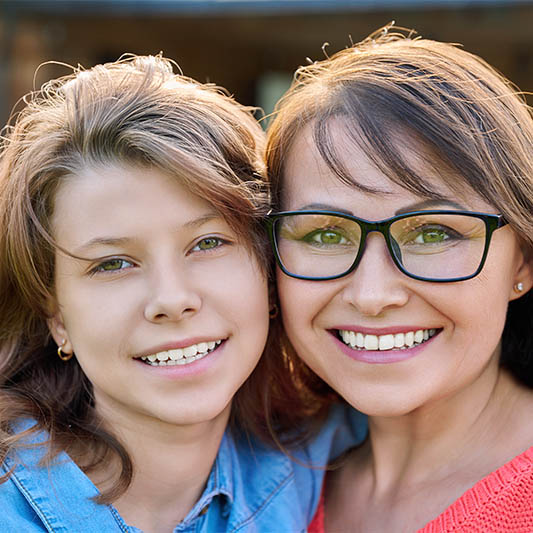 Portrait of happy mom and teenage daughter looking at camera